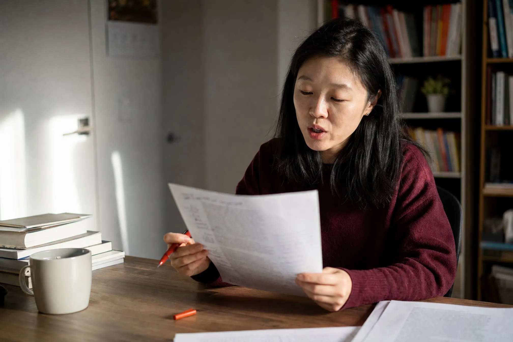 An author reading her printed draft aloud, margins full of her handwritten rewrites